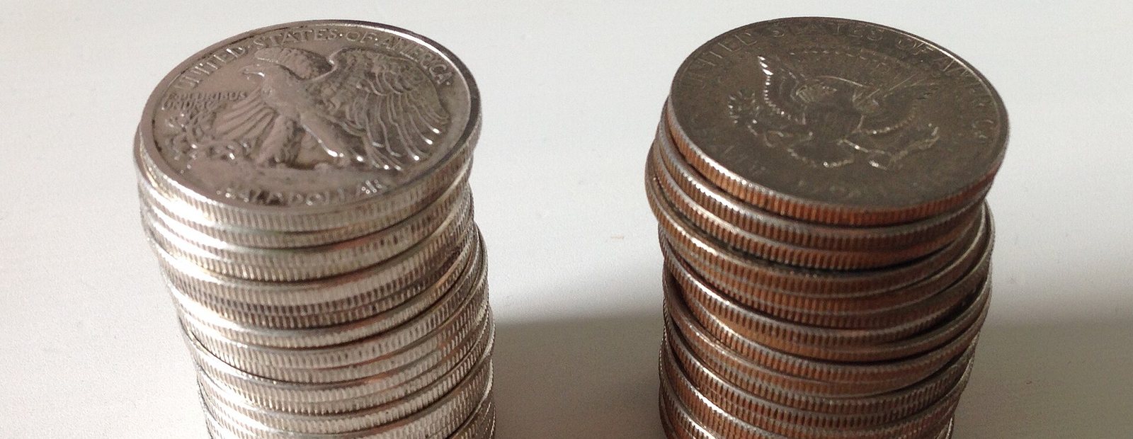 Two stacks of coins side by side. The left stack has plain silver edges. The right stack shows an orange copper stripe running through every coin.